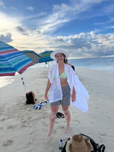 a woman standing on the beach with a towel at Konut by Thakuru in Guraidhoo