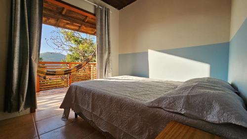 a bedroom with a bed and a large window at Vila no Rosa Hospedaria in Praia do Rosa