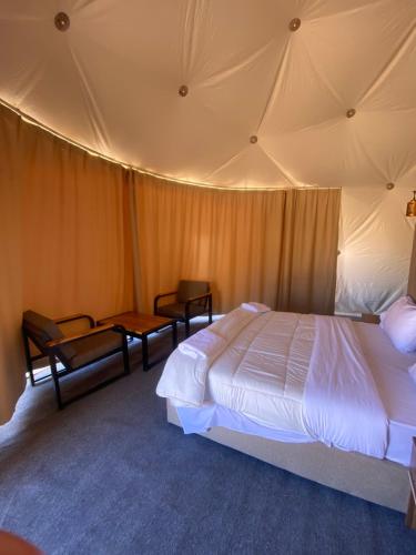 a bedroom with a bed and chairs in a tent at Wadi Rum Santa Camp in Wadi Rum