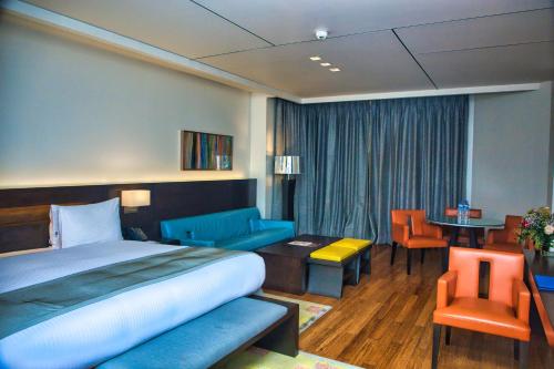 ラゴスにあるEko Hotel Signatureのベッド、テーブル、椅子が備わるホテルルームです。