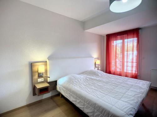 une chambre avec un lit blanc et une fenêtre dans l'établissement Bel F2 climatisé, terrasse, parking, à 50m des Thermes de Lamalou-les-Bains, animaux acceptés - FR-1-451-193, à Lamalou-les-Bains