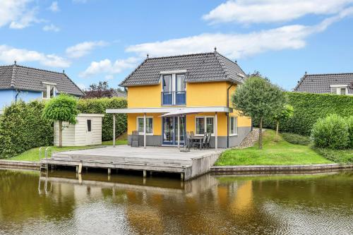 a yellow house on a dock next to a body of water at Summio Waterpark De Bloemert in Zuidlaren