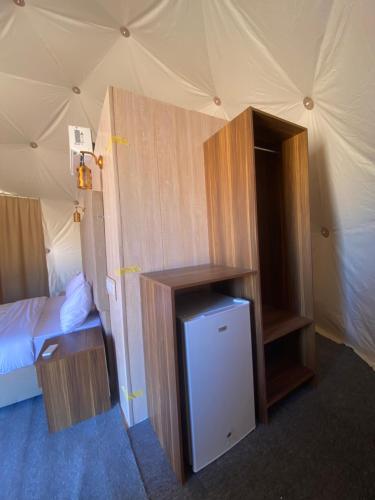 a room with a bed and a refrigerator in a tent at Wadi Rum Santa Camp in Wadi Rum