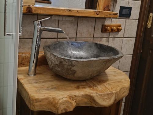 - un évier en pierre sur un comptoir en bois avec un robinet dans l'établissement Sauze d'Oulx with garden, ciabot la garitüla - wifi, à Sauze dʼOulx