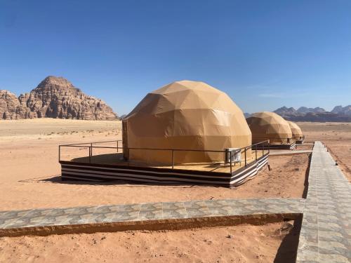 two domes in the desert with mountains in the background at Wadi Rum Santa Camp in Wadi Rum