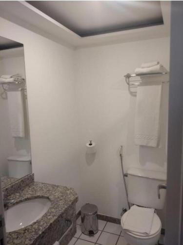 a white bathroom with a toilet and a sink at Praia do Canto Apart Hotel - Apto 102B in Vitória