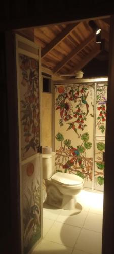 a bathroom with a toilet and paintings on the walls at Hospedaje Rural Tupinamba in Ibagué