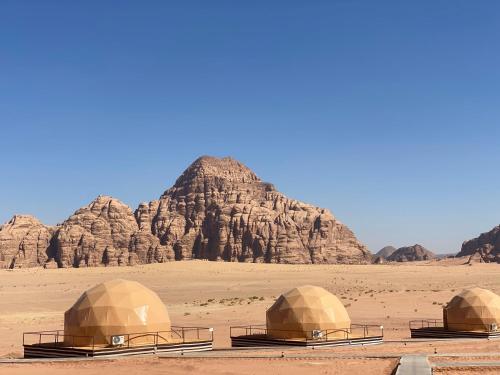 three domes in the desert with mountains in the background at Wadi Rum Santa Camp in Wadi Rum