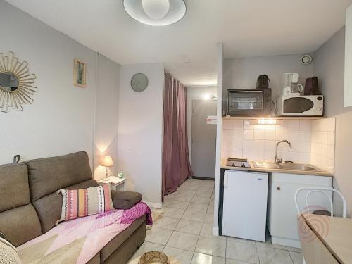uma sala de estar com um sofá e uma cozinha em Studio Lamalou-les-Bains, 1 pièce, 2 personnes - FR-1-451-197 em Lamalou-les-Bains