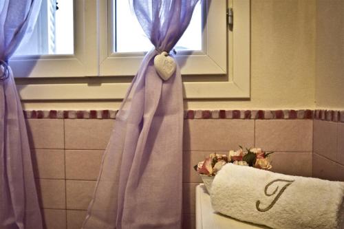 a bathroom with purple curtains and a towel at B&B Zelmirà in Rimini