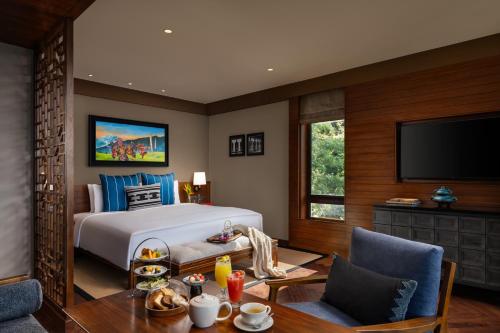 a bedroom with a bed and a table and a tv at Taj Guras Kutir Resort & Spa, Gangtok in Gangtok