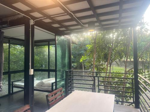 a glass house with a bed on a balcony at ชลลดา ริเวอร์ โฮมสเตย์ แก่งกระจาน in Ban Wang Malako