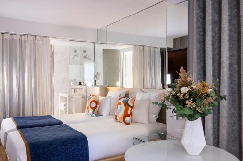 - une chambre avec un lit blanc et un grand miroir dans l'établissement Le 7 Eiffel Hotel by Malone, à Paris