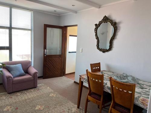 een woonkamer met een tafel, een stoel en een spiegel bij Peaceful Perch in Walvis Bay