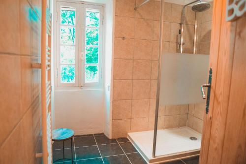 a bathroom with a shower with a window and a stool at Le Moulin de L'Isle - Maison chaleureuse in LʼIsle-Bouzon