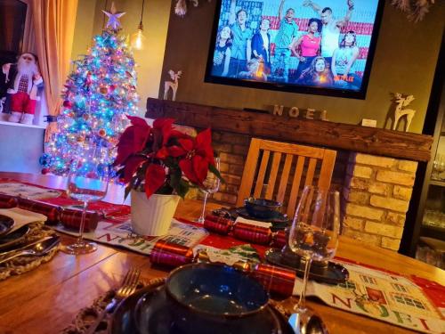a dining room table with a christmas tree and a television at Beresford Cottage in Skegness