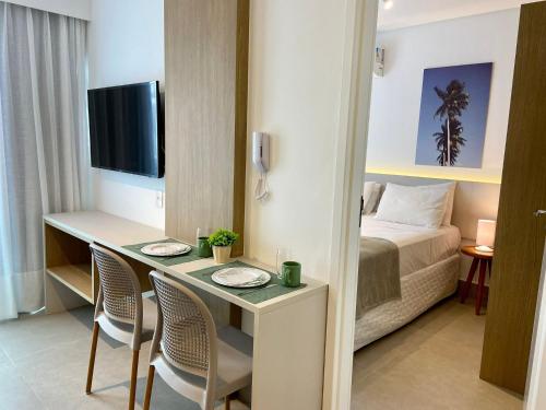 a hotel room with a bed and a desk with chairs at Green Porto 207 -Flat premium no centro de Porto in Ipojuca