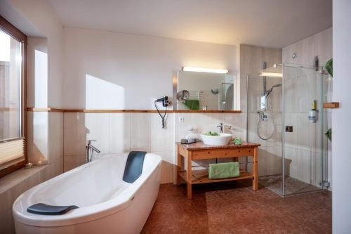 ein Bad mit einer Badewanne, einer Dusche und einem Waschbecken in der Unterkunft Natur- & Wanderhotel Tuxertal in Tux