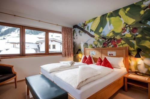 a bedroom with a large white bed with red pillows at Natur- & Wanderhotel Tuxertal in Tux