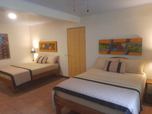 a bedroom with two beds and paintings on the walls at Coyaba Tropical Elegant Adult Guesthouse in Manuel Antonio