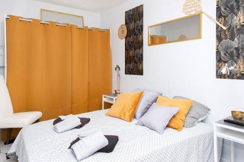 ein Schlafzimmer mit einem Bett mit orangefarbenen und grauen Kissen in der Unterkunft L'Ambre - Appt au cœur de la Normandie in Brionne