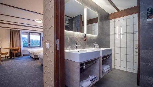 a bathroom with a sink and a bedroom with two beds at Fletcher Hotel-Restaurant de Witte Brug in Lekkerkerk