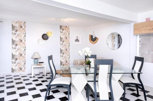 - une salle à manger avec une table en verre et un sol en damier noir et blanc dans l'établissement L'Ambre - Appt au cœur de la Normandie, à Brionne