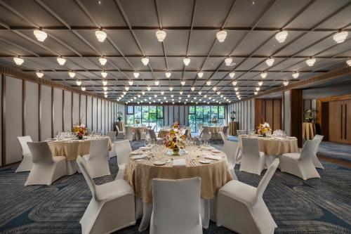 a banquet room with tables and white chairs at Taj Guras Kutir Resort & Spa, Gangtok in Gangtok