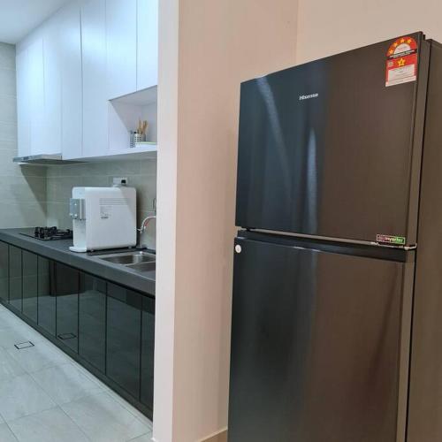 a black refrigerator in a kitchen with a sink at THE COVE at D'Garden City Centre in Batu Pahat