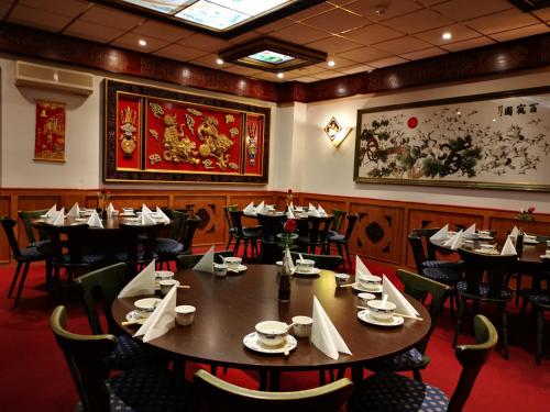 a dining room with tables and chairs and a painting on the wall at China Restaurant Hotel Lotus in Rothenburg ob der Tauber