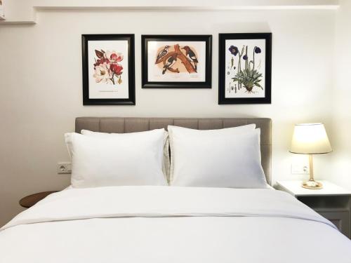 a bedroom with a white bed with four pictures on the wall at MY FABULOUS TRENDY HOME İN TAKSİM SQUARE in Istanbul