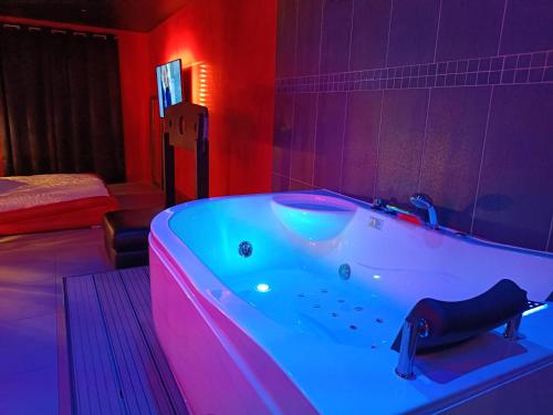 a bath tub in a room with red and purple lighting at Appartement balnéo et sauna privés The Red Room in Mauguio