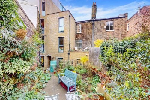 a garden with a blue bench in front of a building at Stunning 2 bed flat with a garden in New Cross in London
