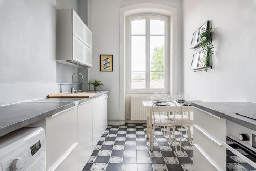 eine Küche mit weißen Schränken und einem schwarz-weißen Fliesenboden in der Unterkunft Harmonie 3 Chambres - spacieux in Saint-Étienne