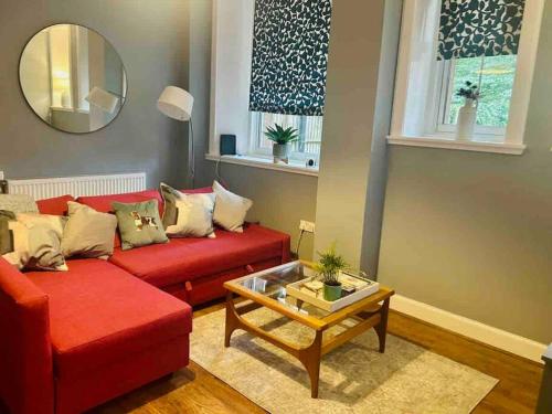 a living room with a red couch and a table at Ground Floor Flat Close to city in Edinburgh