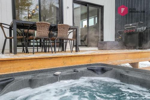 a hot tub on a porch with chairs and a table at Le Blanc Bouleau de Portneuf / Private Hot tub in Pont-Rouge