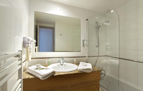 La salle de bains est pourvue d'un lavabo, d'une douche et d'un miroir. dans l'établissement Odalys Hotel New Solarium, à Courchevel