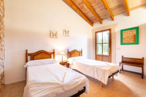 2 bedden in een kamer met witte muren en houten plafonds bij Son Suau Vell by Mallorca House Rent in Felanitx