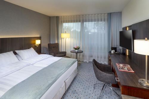 Habitación de hotel con cama grande y escritorio. en Maritim Hotel Bremen en Bremen