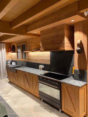 a kitchen with wooden cabinets and a stove top oven at Chalet Jardin Alpin Valberg in Péone