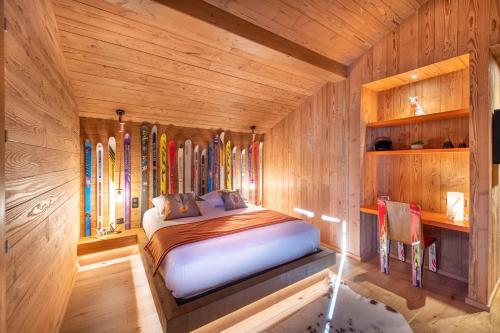 um quarto com uma cama num quarto de madeira com esquis em Chalet Jardin Alpin Valberg em Péone