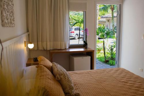 a bedroom with a bed and a door to a yard at Casa Hotel Sahy in Barra do Sahy