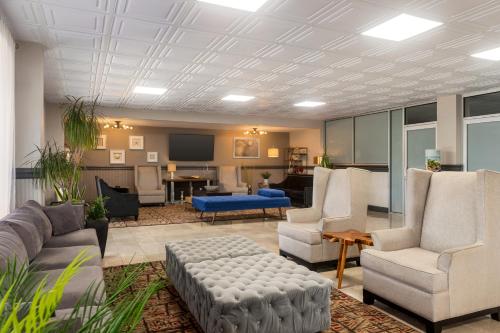 a living room with a couch and chairs and a tv at Ramada by Wyndham Sarasota Waterfront in Sarasota