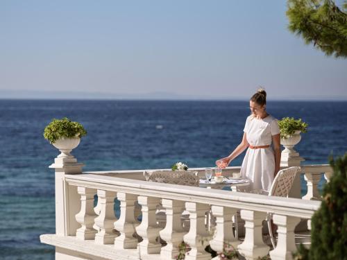 a woman standing on a balcony near the ocean at The Danai in Nikiti