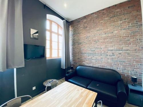 a living room with a blue couch and a brick wall at L'indus Bel appart' Loft TGV-Parking in Saint-Étienne