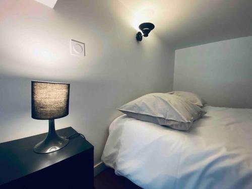 a bedroom with a bed with a lamp on a table at L'indus Bel appart' Loft TGV-Parking in Saint-Étienne