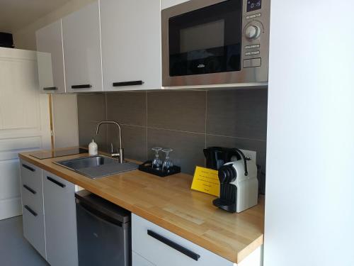 une cuisine avec un évier et un micro-ondes dans l'établissement Appartement balnéo et sauna privés The Red Room, à Mauguio