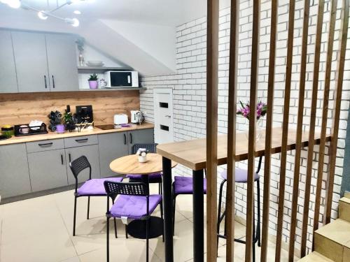 a kitchen with a wooden table and purple chairs at Like Home Hostel na Timiryazeva in Almaty