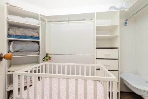 a white nursery with a crib and a sink at Hallett Cove House 6Bed 3Bath Full Kitchen Fast Wifi 5TV Netflix Espresso-Perfect for large families in Halletts Cove