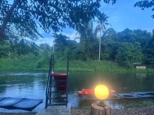 a dock with a boat and a light in the water at ชลลดา ริเวอร์ โฮมสเตย์ แก่งกระจาน in Ban Wang Malako